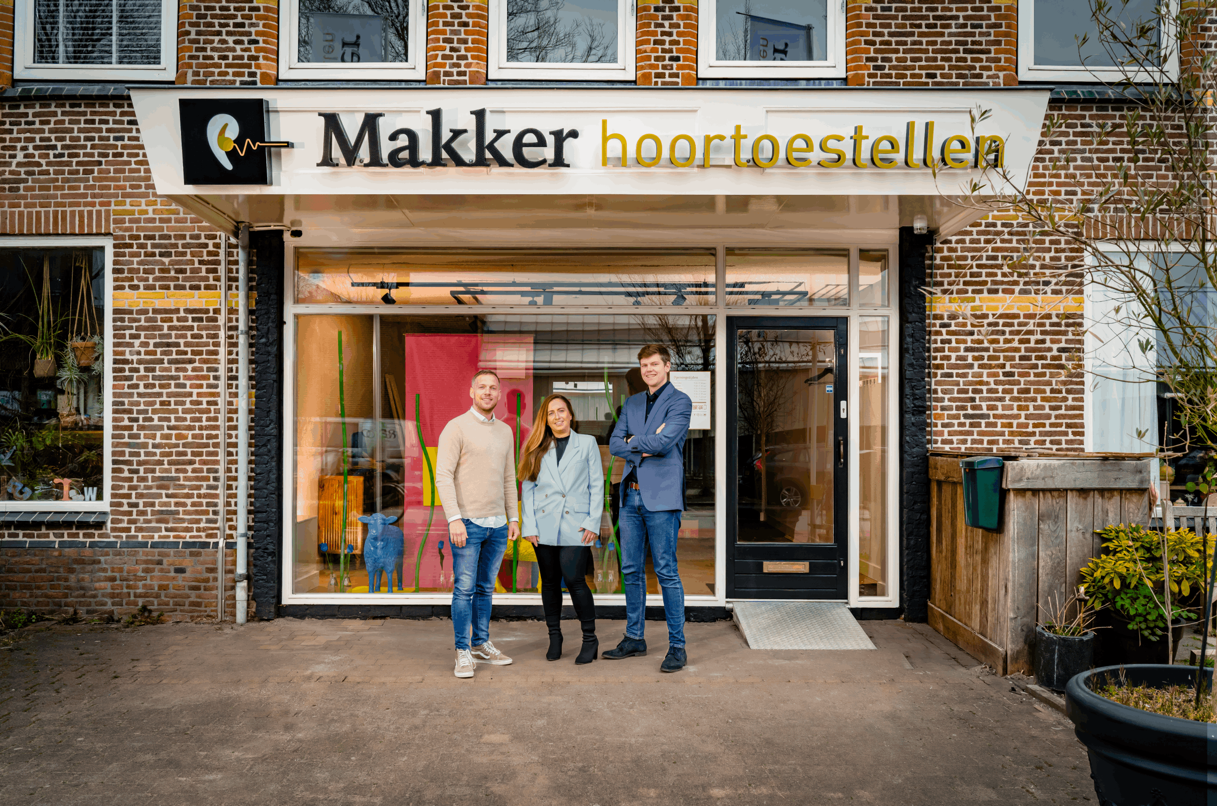 Drie audiciens staan voor de winkel van Makker Hoortoestellen in Amstelveen.