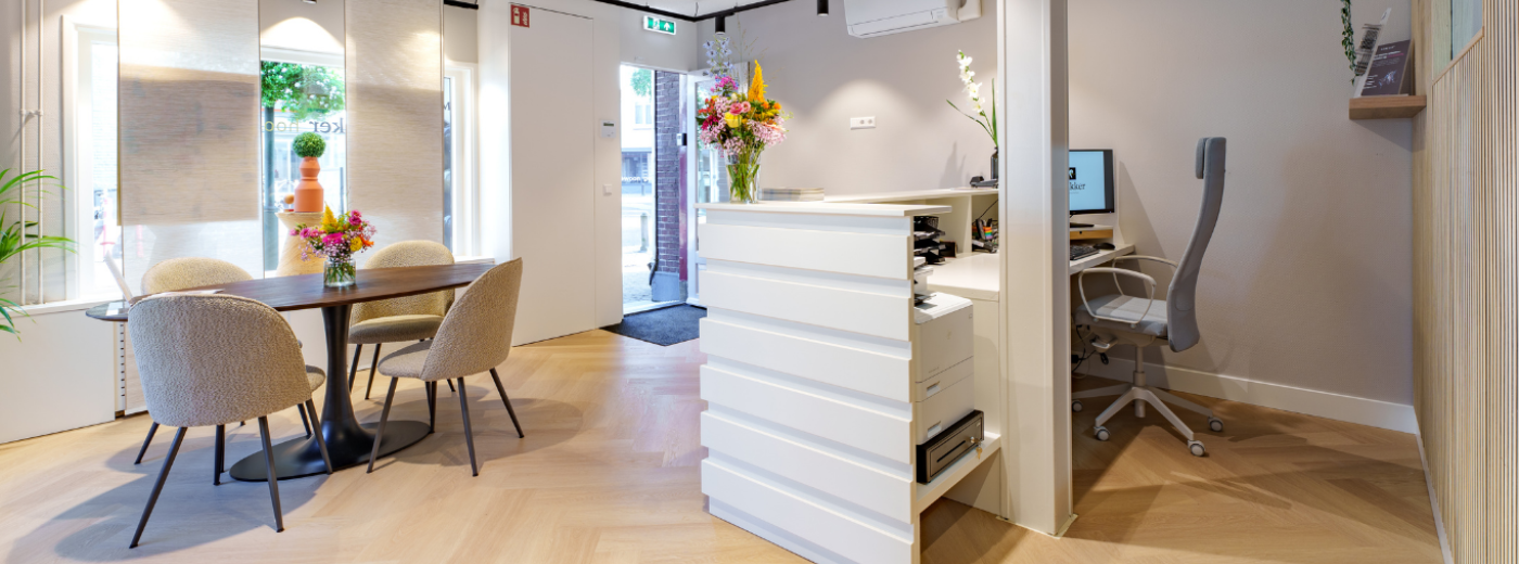 Moderne en sfeervol ingerichte ontvangstruimte met receptiebalie, zitgedeelte en bloemen.