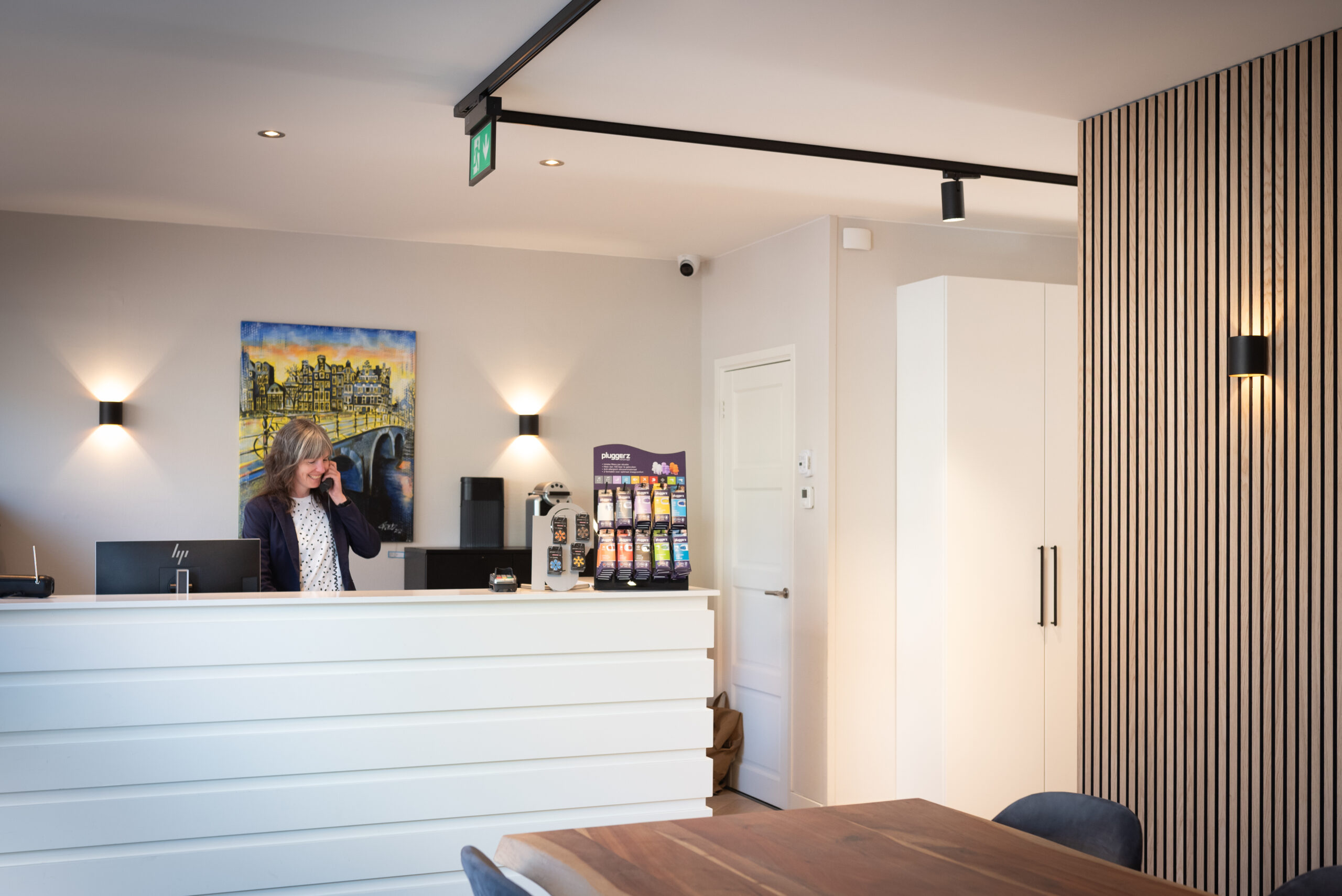 Receptioniste aan balie in modern kantoor met schilderij van Amsterdam op de achtergrond.