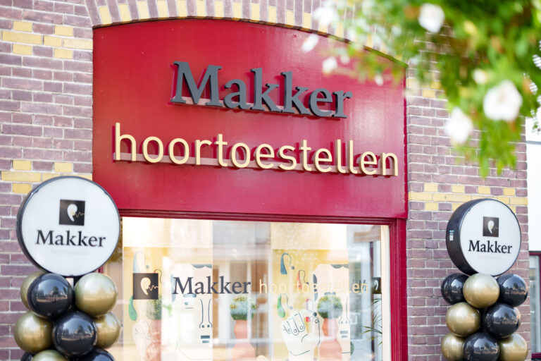 Voorgevel van de hoorwinkel Makker Hoortoestellen met rode gevel en decoratieve ballonnen.