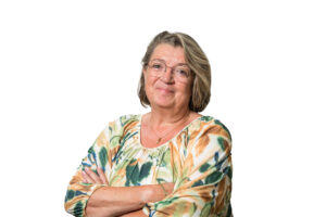 Portret van een vrouw met een bril en een kleurrijke blouse voor een witte achtergrond.