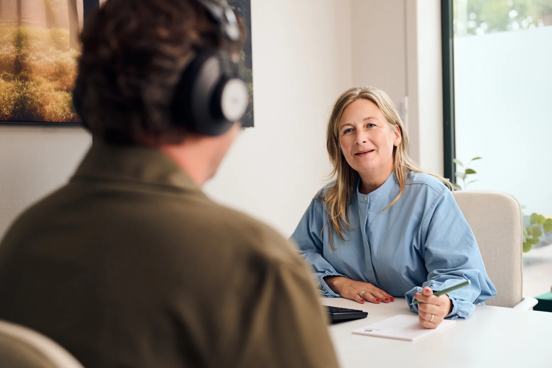 Audicien houdt een in-het-oor hoortoestel vast en bereidt zich voor om het in het oor van een klant te plaatsen.